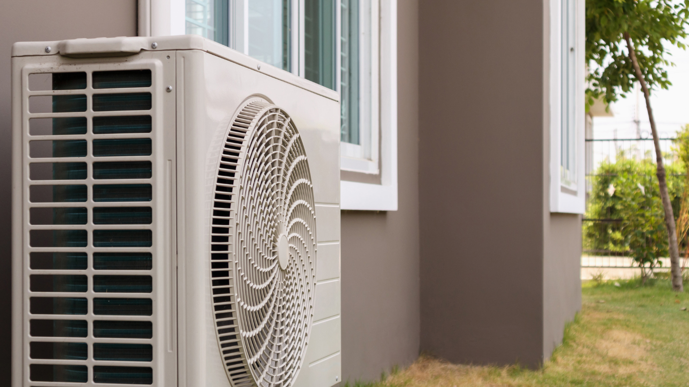 A white air conditioner sitting on the side of a building